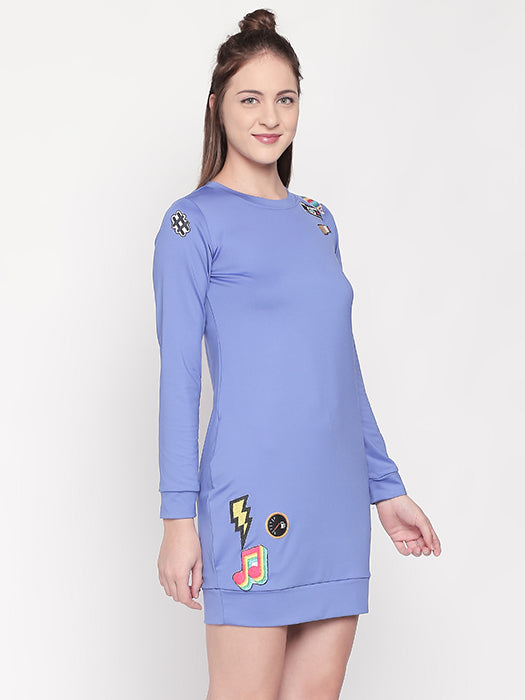 Woman wearing the Cool Patched Full Sleeve Blue Dress by Tuna London, featuring colorful patch designs and long sleeves—radiating a fresh fashion vibe.