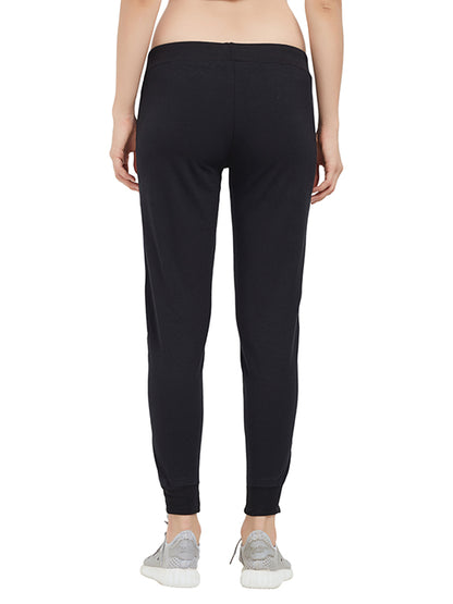 Person seen from the back wearing Classic Joggers TLC02SS—black joggers with a drawstring closure—paired with gray sneakers, set against a white background. An essential addition to any casual wardrobe.