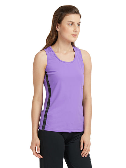 Woman in a purple round neck sleeveless top and black pants stands against a white background, showcasing stylish gym wear made with moisture-wicking fabric.