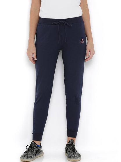 Wearing Blue Classic Joggers TLC04 with adjustable fit, a white t-shirt, and black sneakers, standing against a white background—ideal for stylish lounging.